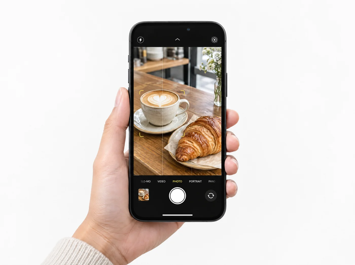 A phone camera framing a latte and a croissant